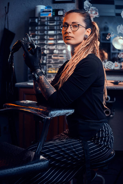 Retrato de mujer joven atractiva con máquina de tatuaje en las manos
 - Foto, imagen