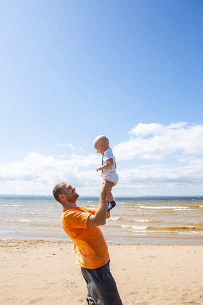 Happy father plays with little son on the street, on the beach. Family, parenthood and people concept - Fotoğraf, Görsel