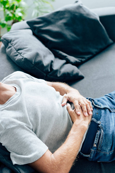cropped view of man in t-shirt and jeans with stomachache  - Foto, Bild
