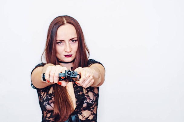 Γυναίκα με δαντέλα και καστανά μαλλιά κρατά ένα όπλο στο χέρι της, στοχεύσατε - Φωτογραφία, εικόνα