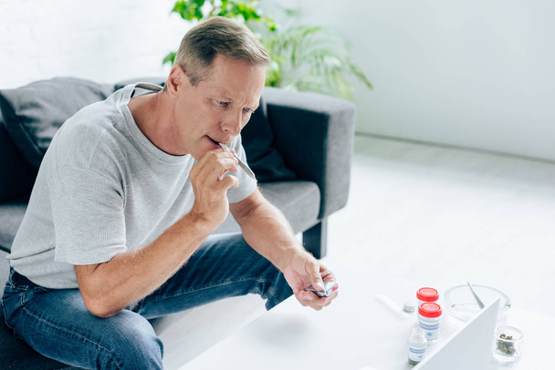 handsome man in t-shirt smoking blunt with medical cannabis - Photo, Image