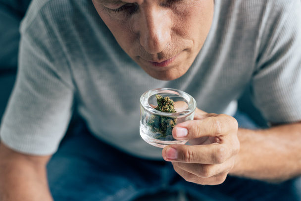 vista recortada del hombre en camiseta oliendo cannabis medicinal en apartamento
  - Foto, Imagen