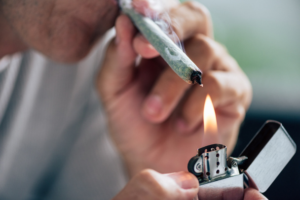 cropped view of man lighting up blunt with medical cannabis - Foto, Imagem