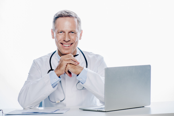 handsome doctor in white coat smiling and looking at camera isolated on white  - Φωτογραφία, εικόνα