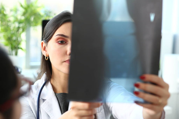 Mujer hermosa médico mantenga en el brazo y mirar a los rayos X
 - Foto, imagen