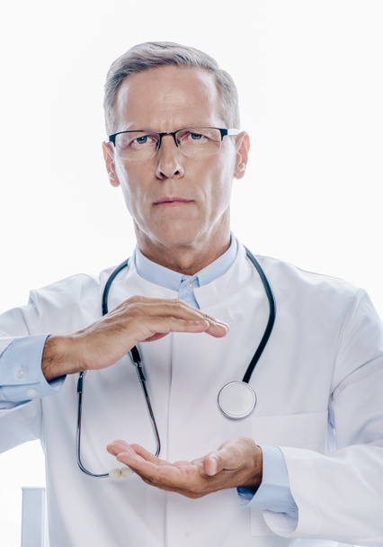 przystojny lekarz w białym płaszczu trzymając ręce na białym tle - Zdjęcie, obraz