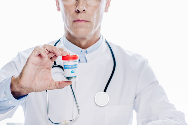 Ausgeschnittene Ansicht eines Arztes im weißen Kittel, der medizinisches Cannabis isoliert auf weiß hält - Foto, Bild