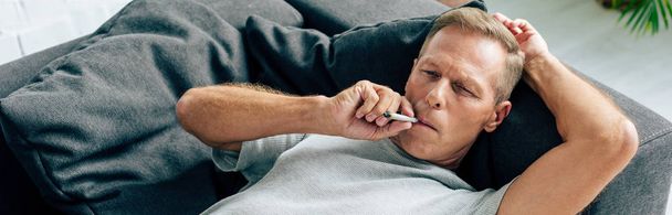 panoramic shot of man smoking blunt with medical cannabis - Foto, afbeelding