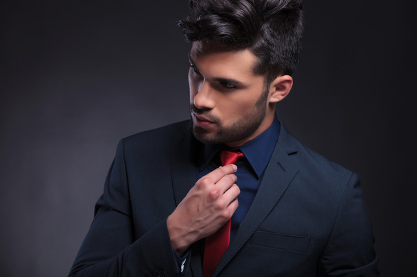 homem de negócios consertando sua gravata e olhando para longe
 - Foto, Imagem
