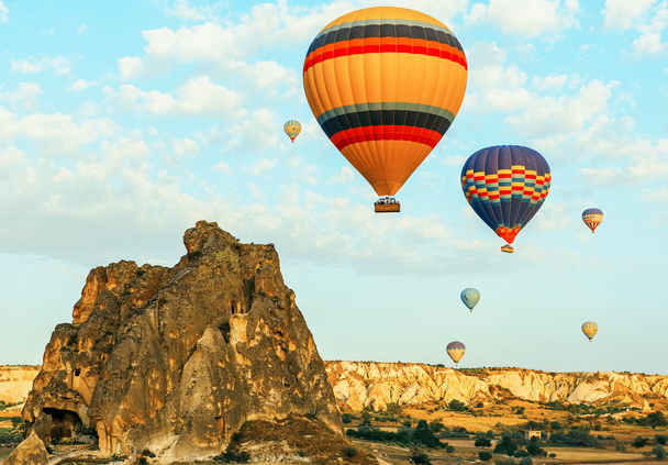 Colorful air balloons fly up into the sky at sunrise among a beautiful rocky landscape. Cappadocia Turkey. - Fotó, kép