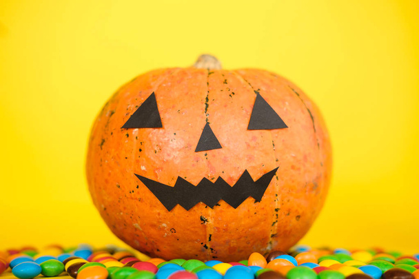 Halloween kurpitsa jack o lyhty sisustus hauska kasvot ja värikäs karkkia keltaisella pohjalla. Hyvää halloween-juhlakonseptia. Karkki tai kepponen. Kopioi tila
  - Valokuva, kuva