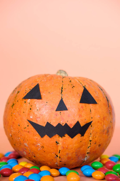 Halloween zucca jack o decorazione lanterna con viso divertente e caramelle colorate su sfondo arancione. Dolcetto o scherzetto. Felice concetto di festa di Halloween. Copia spazio
  - Foto, immagini