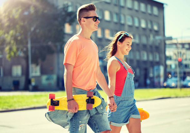 teenage couple with skateboards on city street - Fotó, kép