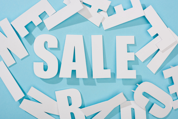 top view of white sale lettering among letters on blue background - Fotó, kép