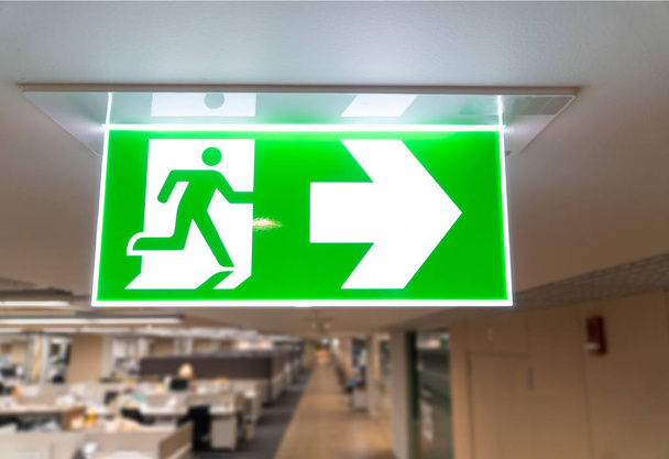 Green fire escape sign hang on the ceiling in the office. - Photo, Image