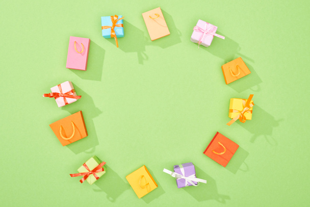 marco redondo de cajas de regalo decorativas y bolsas de compras sobre fondo verde
 - Foto, imagen