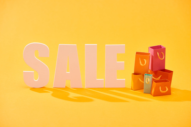 white sale lettering with shopping bags on bright orange background - Photo, Image