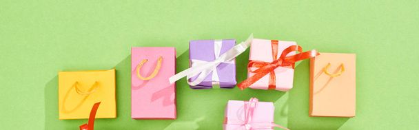 vista superior de coloridas cajas de regalo y bolsas de compras sobre fondo verde, plano panorámico
 - Foto, Imagen