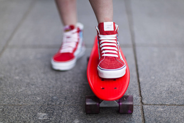 Dziewczyna w czerwonym trampki umieścić jej stopę na deskorolce - Zdjęcie, obraz