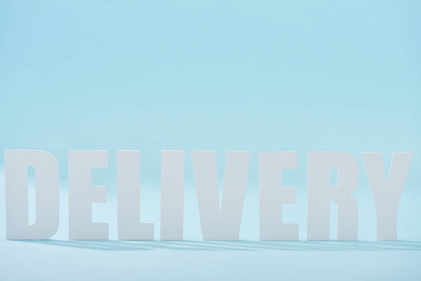 white delivery text with shadows on blue background - Foto, Bild