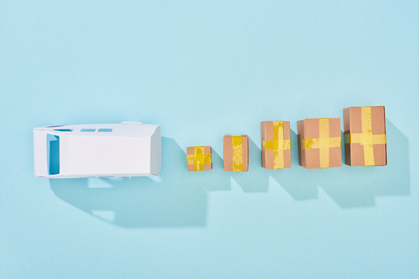 top view of white van model near closed cardboard boxes on blue background - Photo, Image