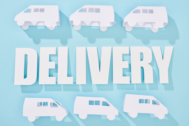 white mini vans around delivery inscription with shadows near blue background - Фото, изображение