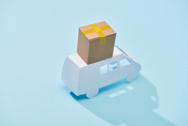 білий міні-фургон з закритою картонною коробкою на ньому на синьому фоні
 - Фото, зображення