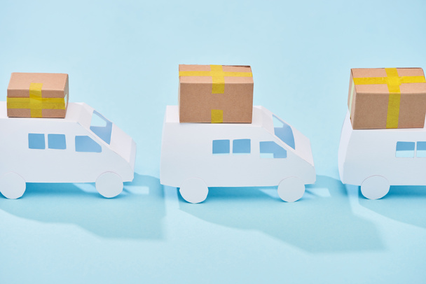 mini furgonetas blancas con cajas de cartón cerradas sobre fondo azul
 - Foto, imagen