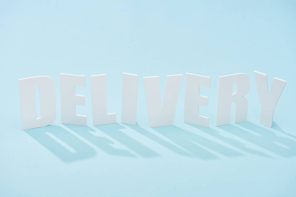 delivery lettering with shadow on blue background with copy space - Foto, afbeelding