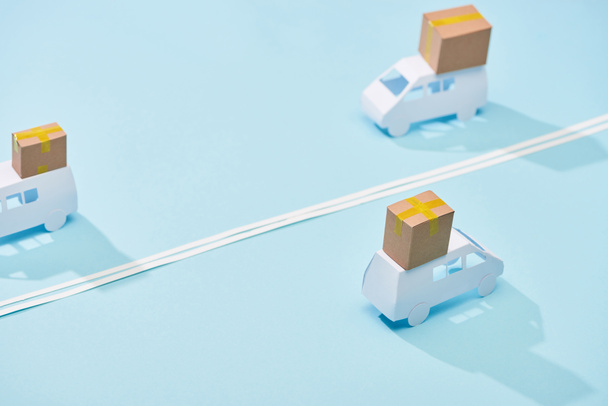 miniature white trucks with parcels on blue background with double line - Photo, Image