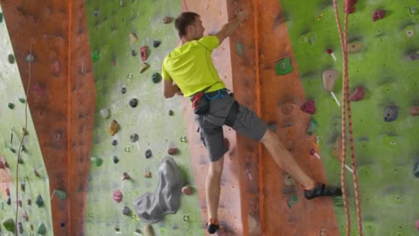 Hegymászás sport tevékenység koncepció: ember mászó a falon. Beltéri hegymászás sport tevékenység koncepció: férfi mászó a mesterséges mászófal - Felvétel, videó