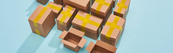 panoramic shot of miniature carton boxes on blue background - Foto, afbeelding
