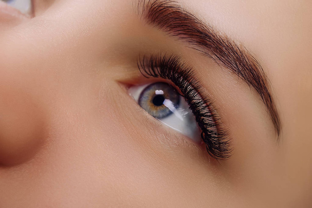 Eyelash Extension Procedure. Woman Eye with Long Blue Eyelashes. Close up, selective focus. - Photo, Image