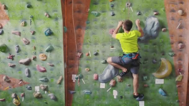 Erkek dağcı odanın uçurum duvarına tırmanıyor. Profesyonel konsantre dağcı duvara doğru hareket eder, kamera yükselir ve hareketlerini bırakır. Boom kamera izle - Video, Çekim