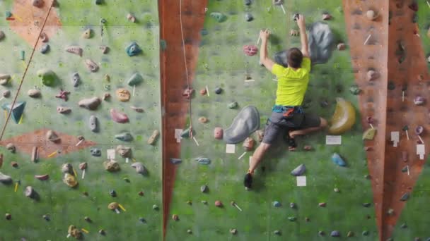 Climbing sport activity concept: Man climber on wall. Indoor climbing sport activity concept: man climber on artificial climbing wall - Footage, Video