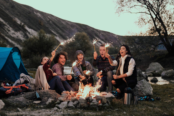Monikilpailu ryhmä nuoria teinejä telttailu tilalla kuohuviini ilotulitus leirinuotiolla yöllä puolue
 - Valokuva, kuva