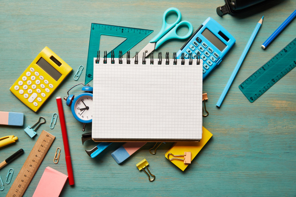 top view of blank notebook near school supplies at turquoise wooden table - Photo, Image