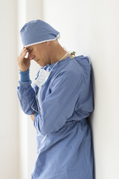 Tensed Male Surgeon With Head In Hands - Foto, afbeelding