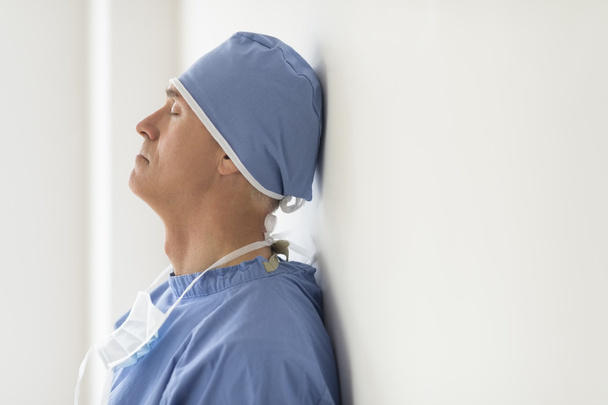 Surgeon With Eyes Closed Leaning On Wall In Ho - Photo, Image