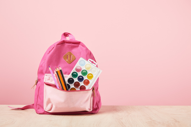rosa Rucksack mit Schulmaterial isoliert auf rosa mit Kopierraum - Foto, Bild