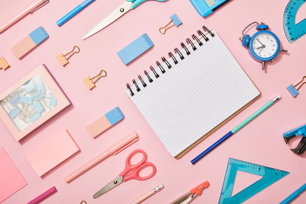 tendido plano con material escolar azul y rosa y cuaderno en blanco aislado en rosa
 - Foto, Imagen
