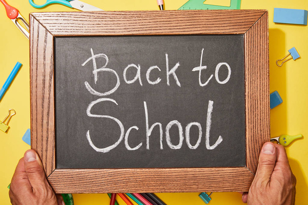 cropped view of man holding chalkboard with back to school lettering - Fotó, kép