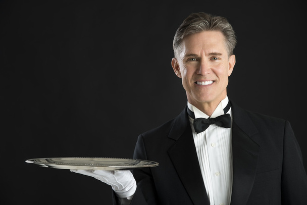 Retrato de camarero confiado en esmoquin con bandeja de servicio
 - Foto, Imagen