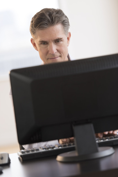 Empresario sonriendo mientras mira el monitor de computadora
 - Foto, imagen