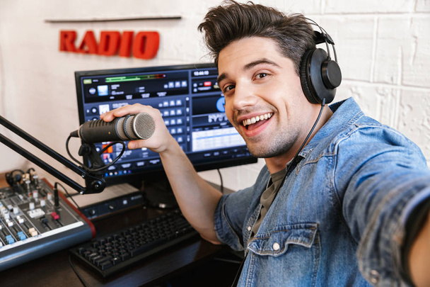 Handsome happy young male radio host broadcasting - 写真・画像