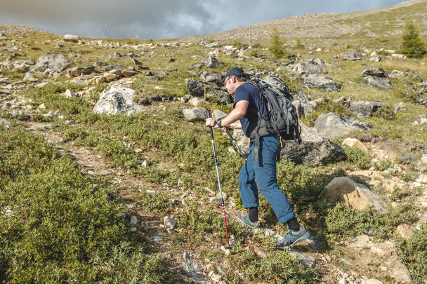 Man Wandelen met rugzak tijdens het beklimmen van de piek in de zomer. Concept trekking reizen en actief leven met de natuur - Foto, afbeelding