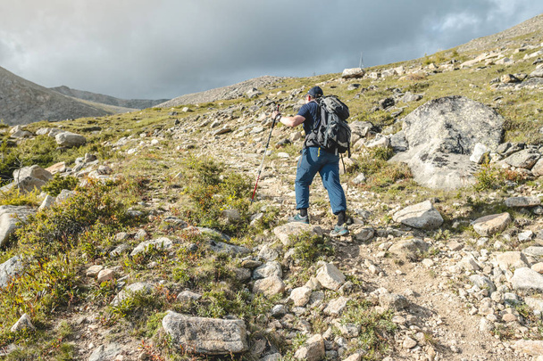 Man Hiking with backpack during the ascent of the peak in the summer. Concept trekking trips and active life with nature - 写真・画像