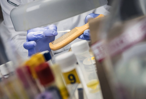 Naukowiec policja trzymać morderstwo ofiara grzebień znaleźć DNA w laboratorium przestępczości, obraz koncepcyjny - Zdjęcie, obraz