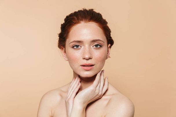 Young redhead woman posing isolated over beige wall background. - Foto, Imagem