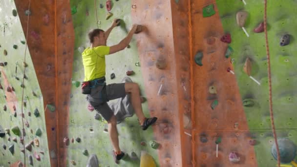 Climbing sport activity concept: Man climber on wall. Indoor climbing sport activity concept: man climber on artificial climbing wall - Footage, Video